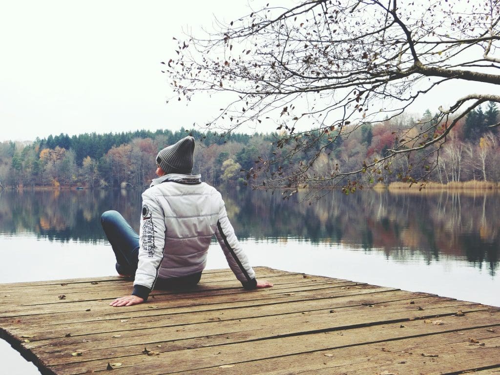 Mentoria Coaching Frau sitzt am See auf in der Natur